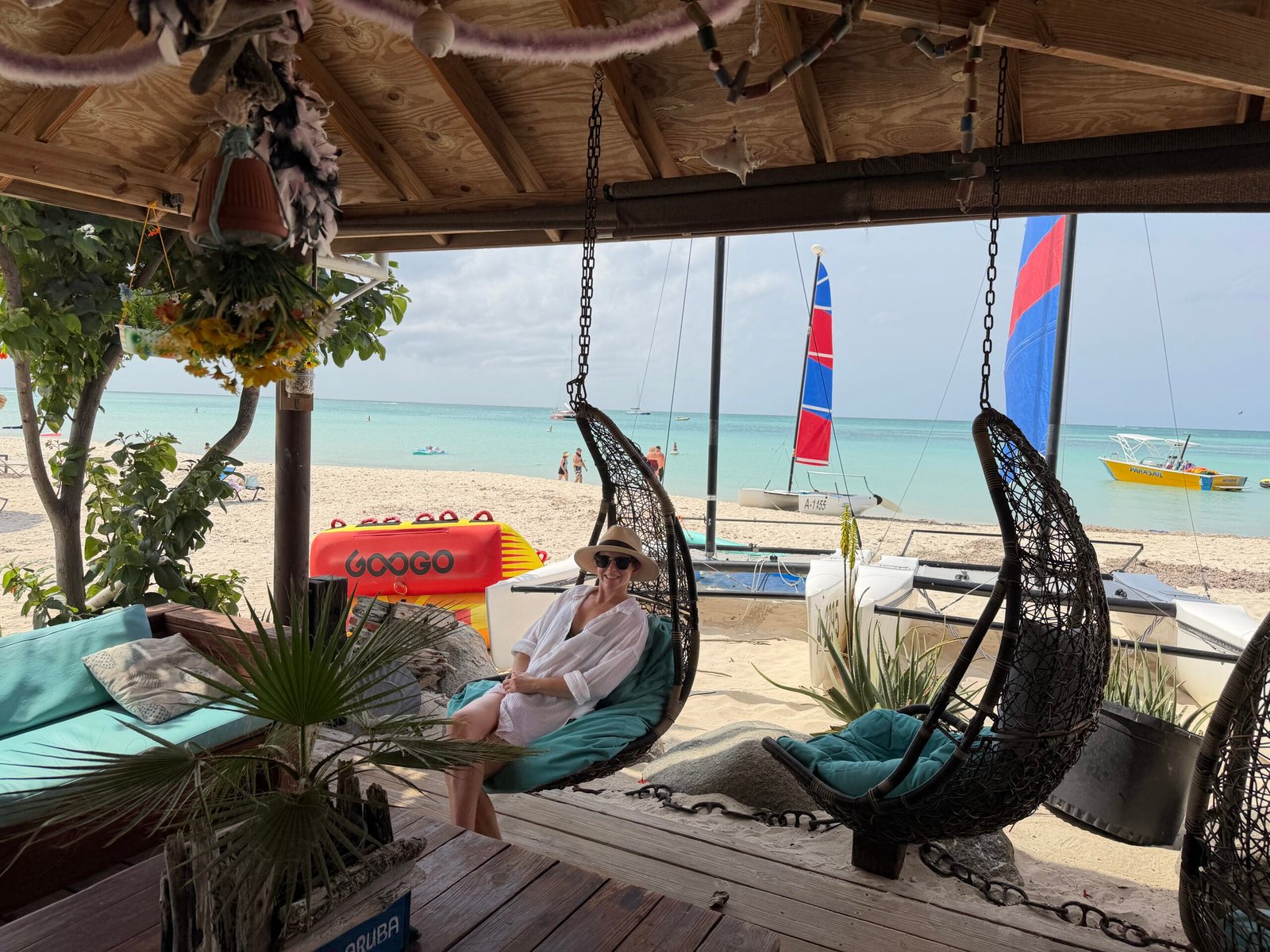 Traveler relaxing in a hanging chair overlooking a turquoise beach in Aruba